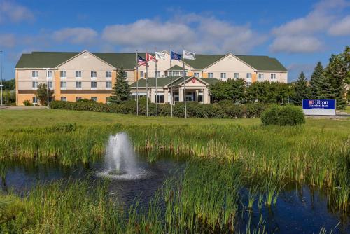 a building with a fountain in the middle of a pond at Hilton Garden Inn Grand Forks-Und in Grand Forks
