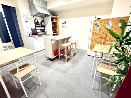 a kitchen with tables and stools in a room at Wabi Sabi Hostel Shinjuku West in Tokyo
