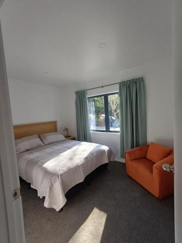 ein Schlafzimmer mit einem Bett und einem Stuhl und einem Fenster in der Unterkunft Nelson Road Apartment in Gisborne