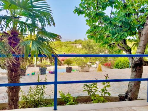 a beach with a blue fence and palm trees at Villa Last Chance, Brač in Povlja