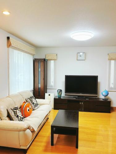a living room with a couch and a flat screen tv at Aki House居住型民泊小岩駅まで送迎あり in Tokyo