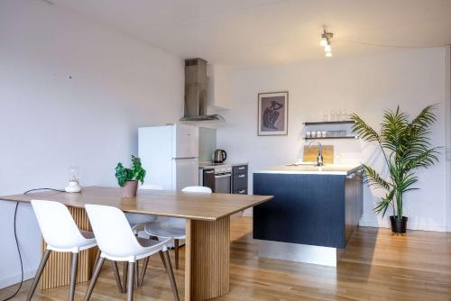 eine Küche mit einem Holztisch und weißen Stühlen in der Unterkunft Frederiksberg stunning apartment in Kopenhagen