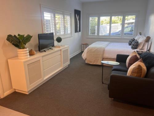 a bedroom with a bed and a tv and a couch at Studio by the bays in Auckland
