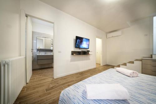 Una habitación blanca con una cama y un televisor en la pared. en Appartamenti La Torre, en Lazise