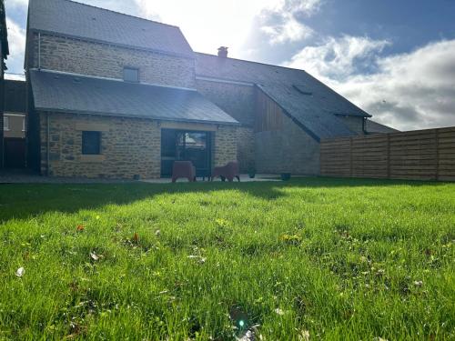 a building with a grass field in front of it at Les Volets Bleus house and spa in Jublains