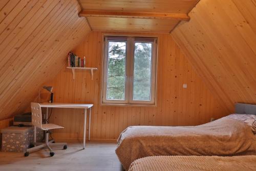 a bedroom with a bed and a desk and a window at Całoroczny, drewniany domek przy lesie in Prażmów