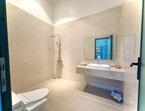 ein Badezimmer mit Waschbecken, Toilette und Spiegel in der Unterkunft Bao Ong Thien Retreat - Khu Nghỉ Dưỡng Bào Ông Thiền 