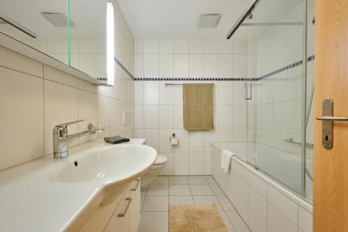 a white bathroom with a sink and a shower at Great Location, Spacious, nice views, modern in Lauterbrunnen