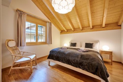 a bedroom with a bed and a chair and a chandelier at Great Location, Spacious, nice views, modern in Lauterbrunnen