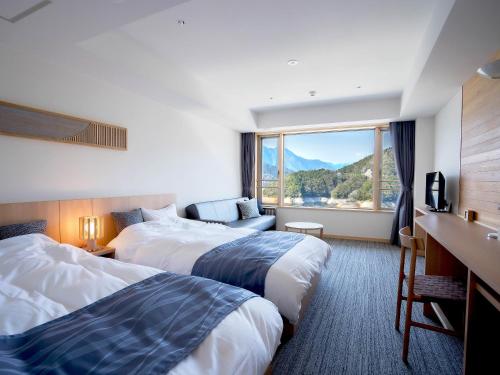 a hotel room with two beds and a window at さめうら荘レイクサイドホテル in Tosa