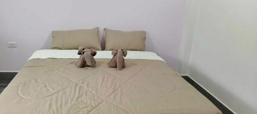 two stuffed elephants sitting on a bed in a bedroom at เจ๊สวนบังกะโล in Ban Dan Mai