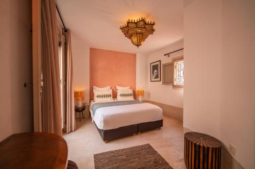 a bedroom with a bed and a chandelier at Riad Dar Amazonia in Marrakesh