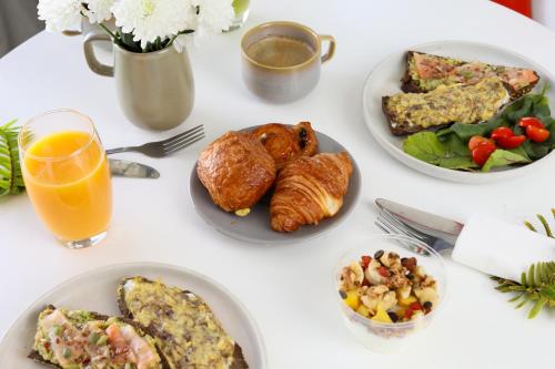 a white table with plates of food and a glass of orange juice at Stayhere Casablanca - Maarif - Elite Residence in Casablanca