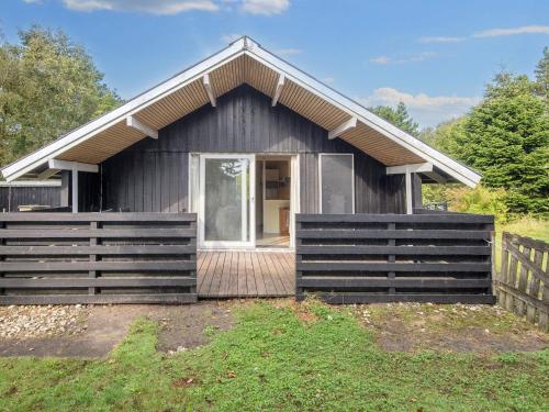een klein zwart huisje met een houten terras bij 4 person holiday home in Skjern in Skjern