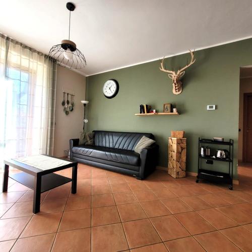 a living room with a couch and a clock on the wall at Villa Glory Mountain Lake Iseo Hospitality in Bossico