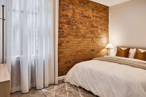 a bedroom with a brick wall and a bed at The Avenue in Launceston