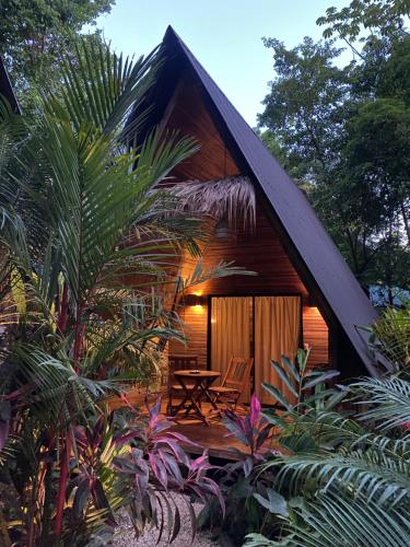 een huisje met een tafel en stoelen in een tuin bij Buena Onda Bungalows in Santa Teresa Beach