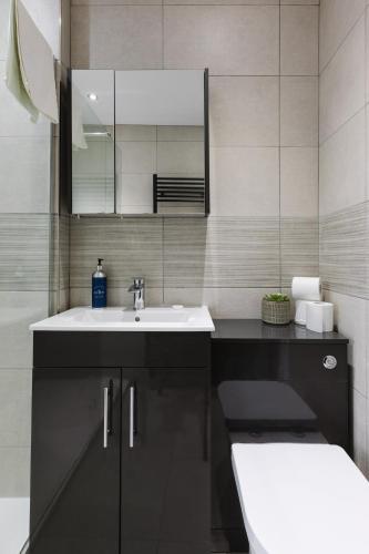 a bathroom with a sink and a mirror at Luxurious 3 Bedroom Home in Belfasts Trendy Lisburn Road Sleeps 6 Modern & Spacious in Belfast