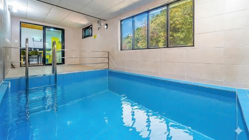 a swimming pool with blue water in a building at Gyeongju Hiltopia Kids Pool Villa in Gyeongju
