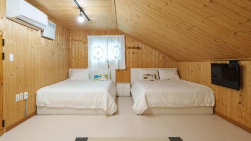 two beds in a room with wooden walls at Gyeongju Hiltopia Kids Pool Villa in Gyeongju