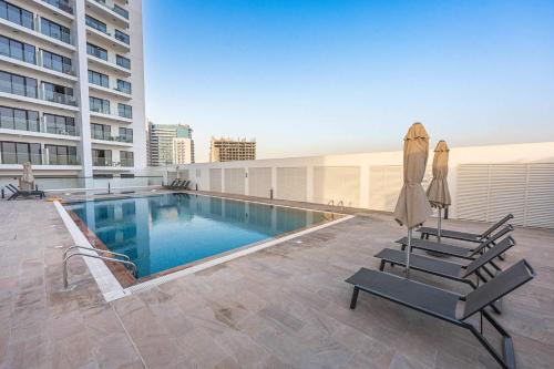 a swimming pool with two chairs and umbrellas on a building at Free housekeeping visits during your stay - StayShort - Jebel Ali Sleeps 2 with a Beautiful Swimming Pool in Dubai