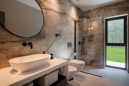 ein Badezimmer mit einem Waschbecken, 2 WCs und einem Spiegel in der Unterkunft Villa Vista Verde in Majkusi