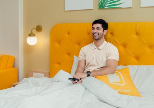 a man sitting on top of a bed at Bloom Hotel - Whitefield in Bangalore