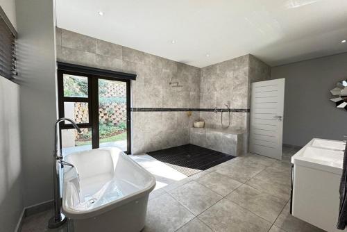 a large bathroom with a tub and a sink at The Coastal Charm Villa in Ballito