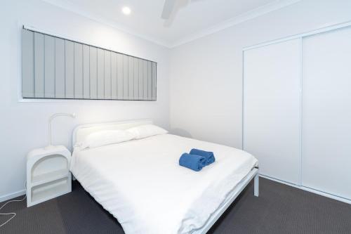 una camera da letto con un letto bianco con una borsa blu sopra di Modern Park Ridge Haven – Perfect for Families! a Marsden