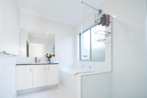 un bagno bianco con lavandino e specchio di Modern Park Ridge Haven – Perfect for Families! a Marsden