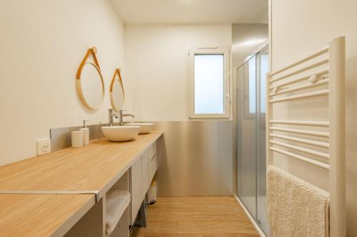 een badkamer met een wastafel en een spiegel bij L'instant fleuri in Saint-Hippolyte