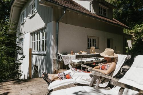 a woman in a hat sitting on a chair on a patio at Waldmaise in Hayingen