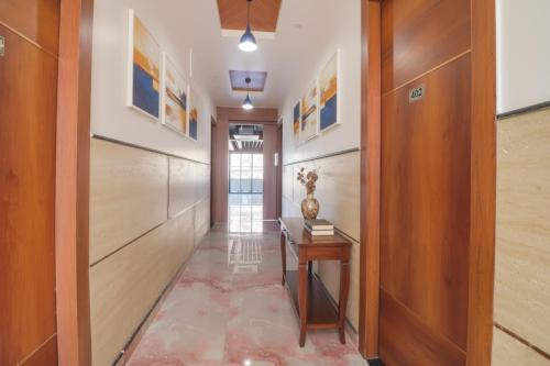 a hallway with a table and a door with paintings at FabHotel Grand Arya in Patna