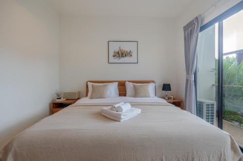 a bedroom with a bed with two towels on it at Uncle Toy in Ban Riang