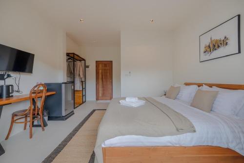 une chambre avec un grand lit et un bureau dans l'établissement Uncle Toy, à Ban Riang