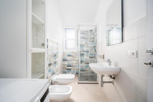 een witte badkamer met 2 toiletten en een wastafel bij Girasole in La Caletta