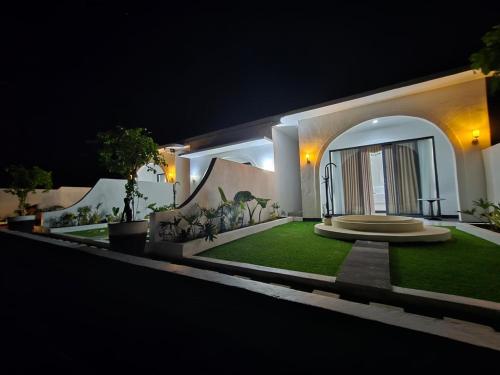 a house with a green lawn in front of it at night at Pinggan Chill Out Kintamani in Gretek