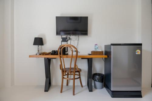 un bureau avec une télévision et une chaise à côté d'un réfrigérateur dans l'établissement Uncle Toy, à Ban Riang