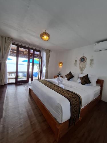 a bedroom with a large bed with a view of the ocean at SEAVIEW Bungalow & Resto in Sekotong