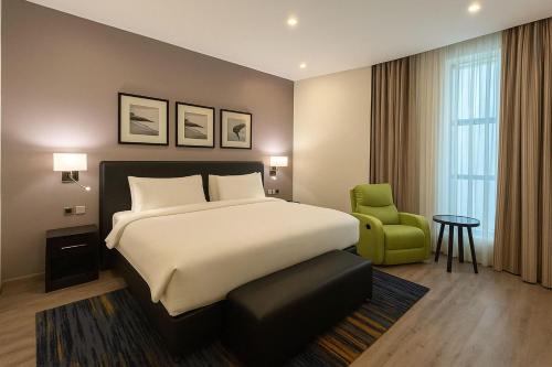 a bedroom with a large bed and a green chair at Radisson Blu Plaza Jeddah in Jeddah