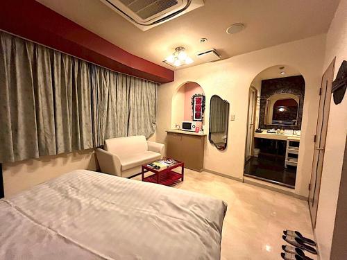 a bedroom with a bed and a chair in a room at ホテルクレアトゥール安城 in Anjomachi