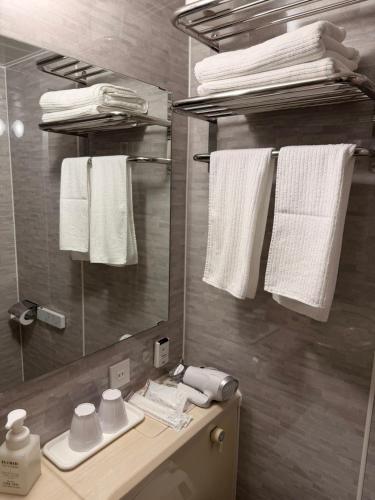 a bathroom with a mirror and white towels at Hotel Tetora Spirit Sapporo in Sapporo
