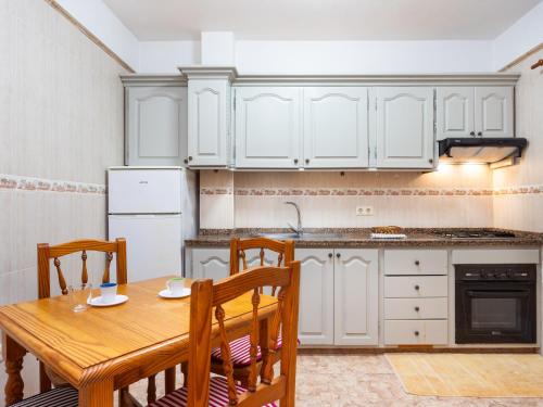 a kitchen with white cabinets and a wooden table and chairs at Live Salinas 3 in Caleta de Interián