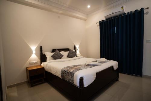 a bedroom with a large bed with a blue curtain at Kesar Villa By DSR Group in Bedla