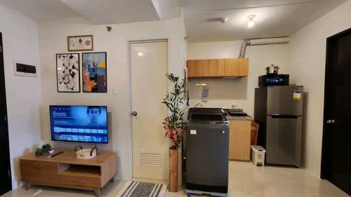 a kitchen with a refrigerator and a tv on the wall at Ann Cozy Living in Cebu City