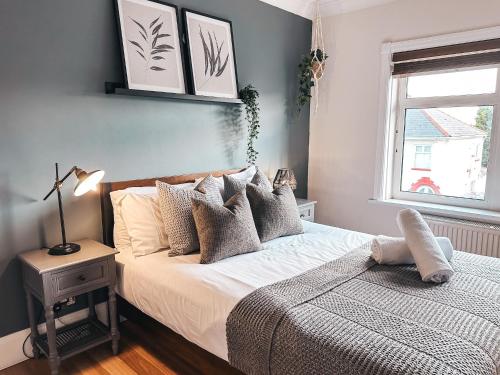 a bedroom with a bed with pillows and a window at Ty-Fry House, by Solace Stays in Cardiff