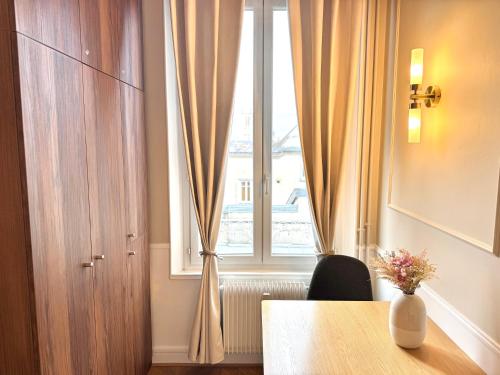 Habitación con mesa y ventana con cortinas. en Le Carrousel - Au Coeur du centre & Wifi, en Troyes