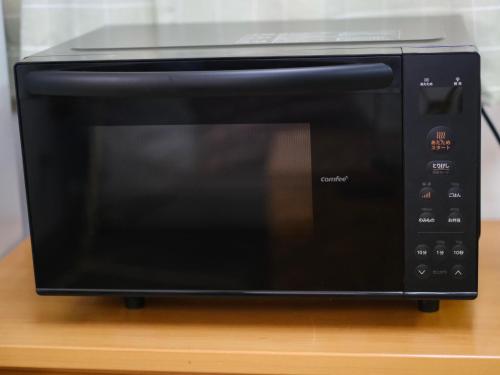 a black microwave oven sitting on top of a table at wanderers Inn in Tanabe