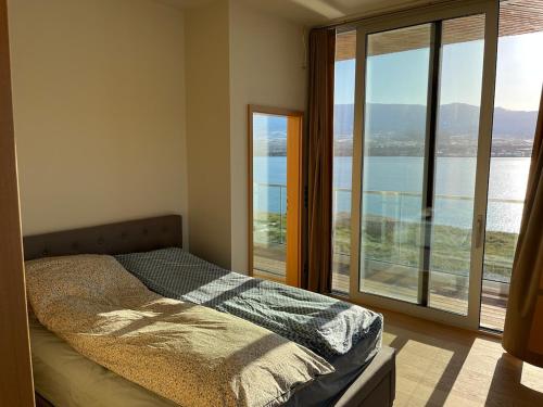 een slaapkamer met een bed voor een groot raam bij Saeluheimur - Oceanside Sanctuary in Akureyri