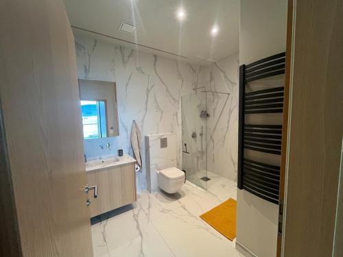 een witte badkamer met een toilet en een wastafel bij Saeluheimur - Oceanside Sanctuary in Akureyri